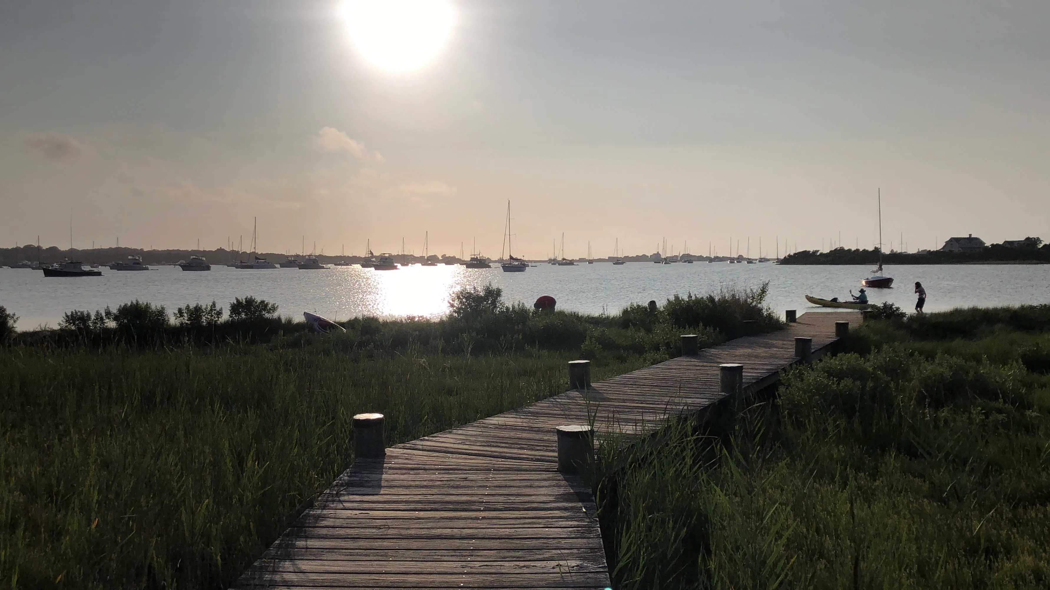 Marsh boardwalk and boats at sunset at Trims Pond